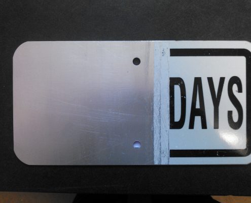 Partially Hydrostripped Aluminum Sign Aluminum traffic sign partially stripped of reflective sheeting to demonstrate the hydrostripping process and exposed bare metal surface.